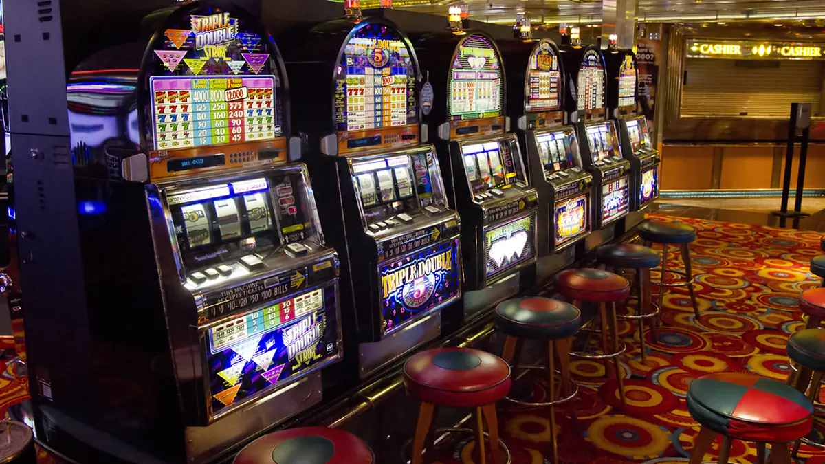 Barisan mesin slot bercahaya di lantai kasino